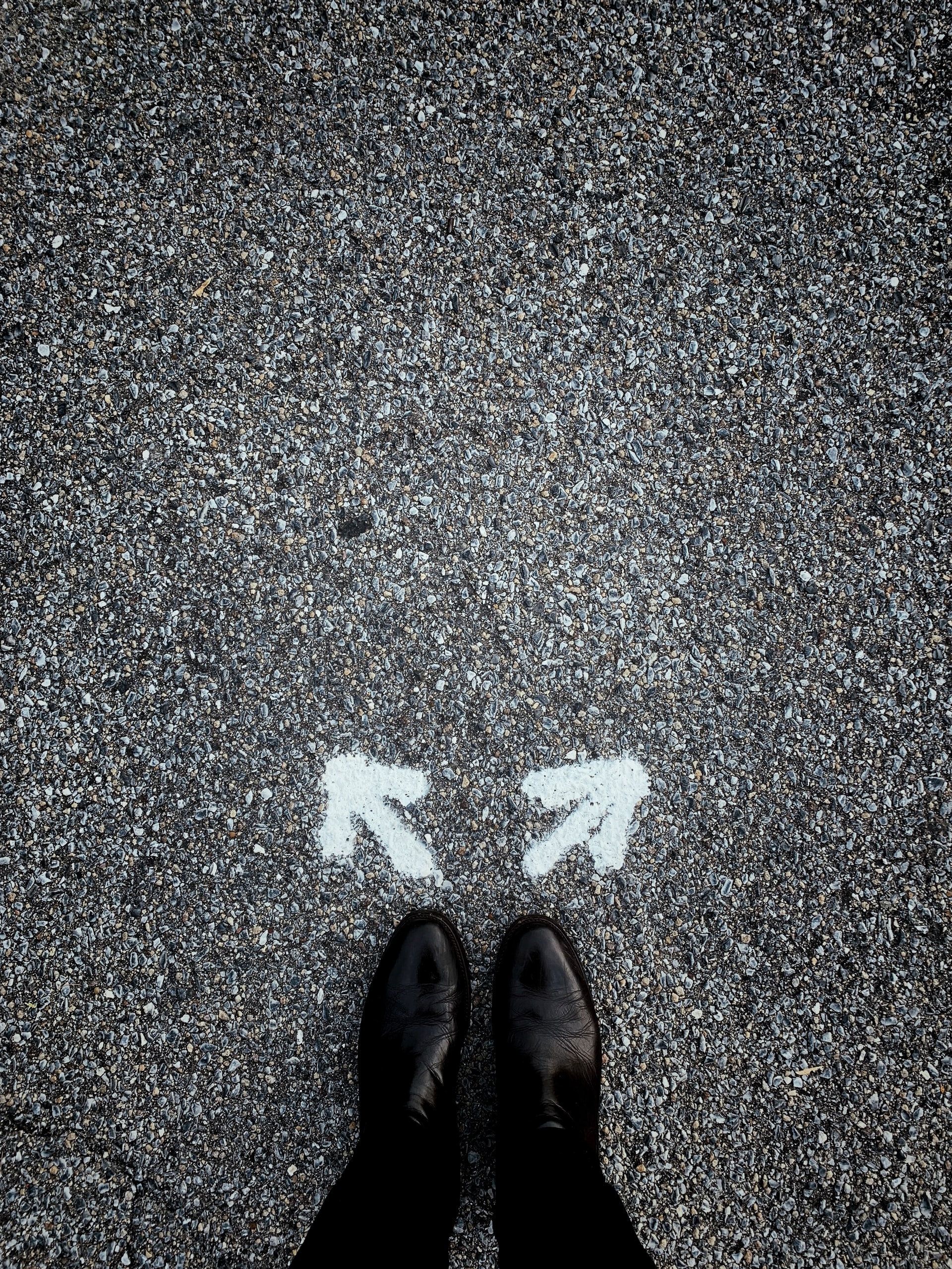 feet with two arrows on asphalt pointing in two directions